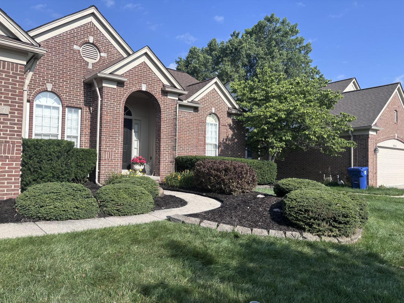 Brick ranch home with freshly edged and mulched beds and rounded shrubs