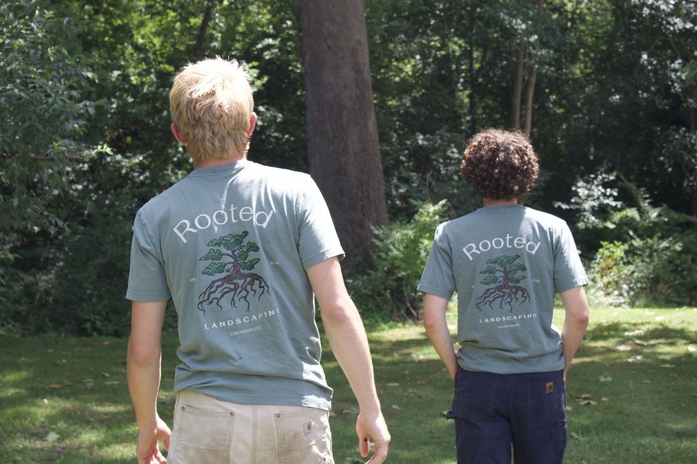 The two owners of Rooted Landscaping in matching Rooted shirts walking across a lawn