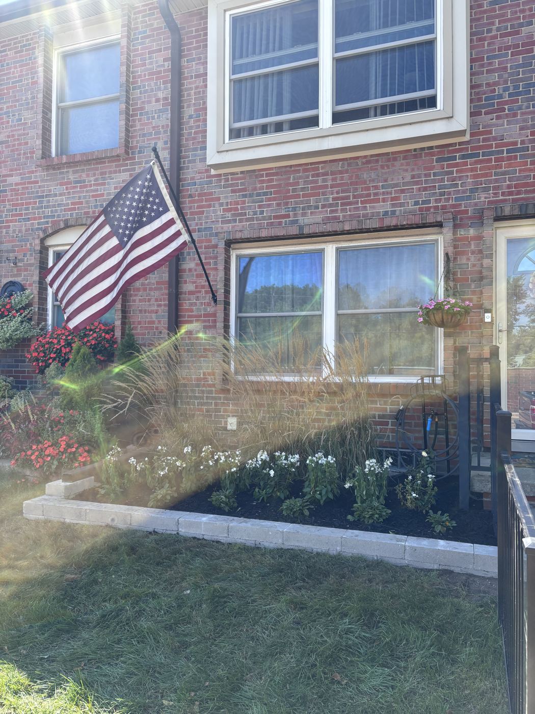 Raised paver bed with ornamental grasses and white phlox